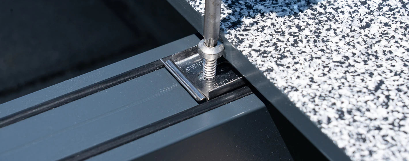 Nahaufnahme der verdeckten Befestigung einer balkoFLOOR Aluminium-Terrassendiele mit einer sandmeir Systemschraube auf der multiTUBE Unterkonstruktion